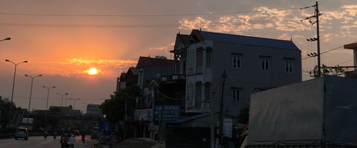 A sunset over a cityscape with buildings and streetlights.