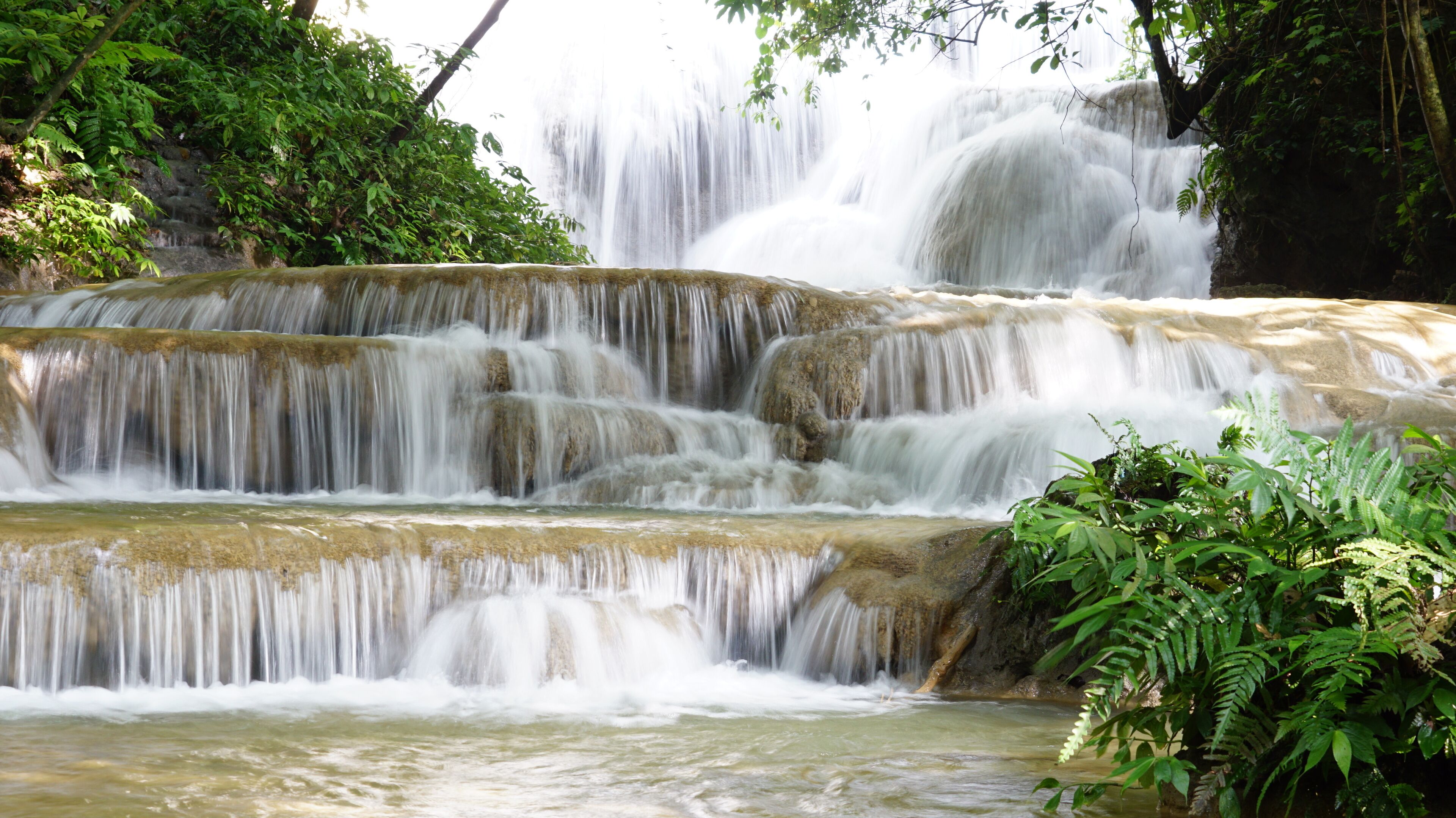 A multi-tiered waterfall surrounded by lush greenery.