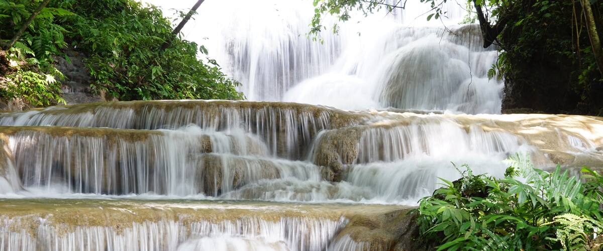 A multi-tiered waterfall surrounded by lush greenery.
