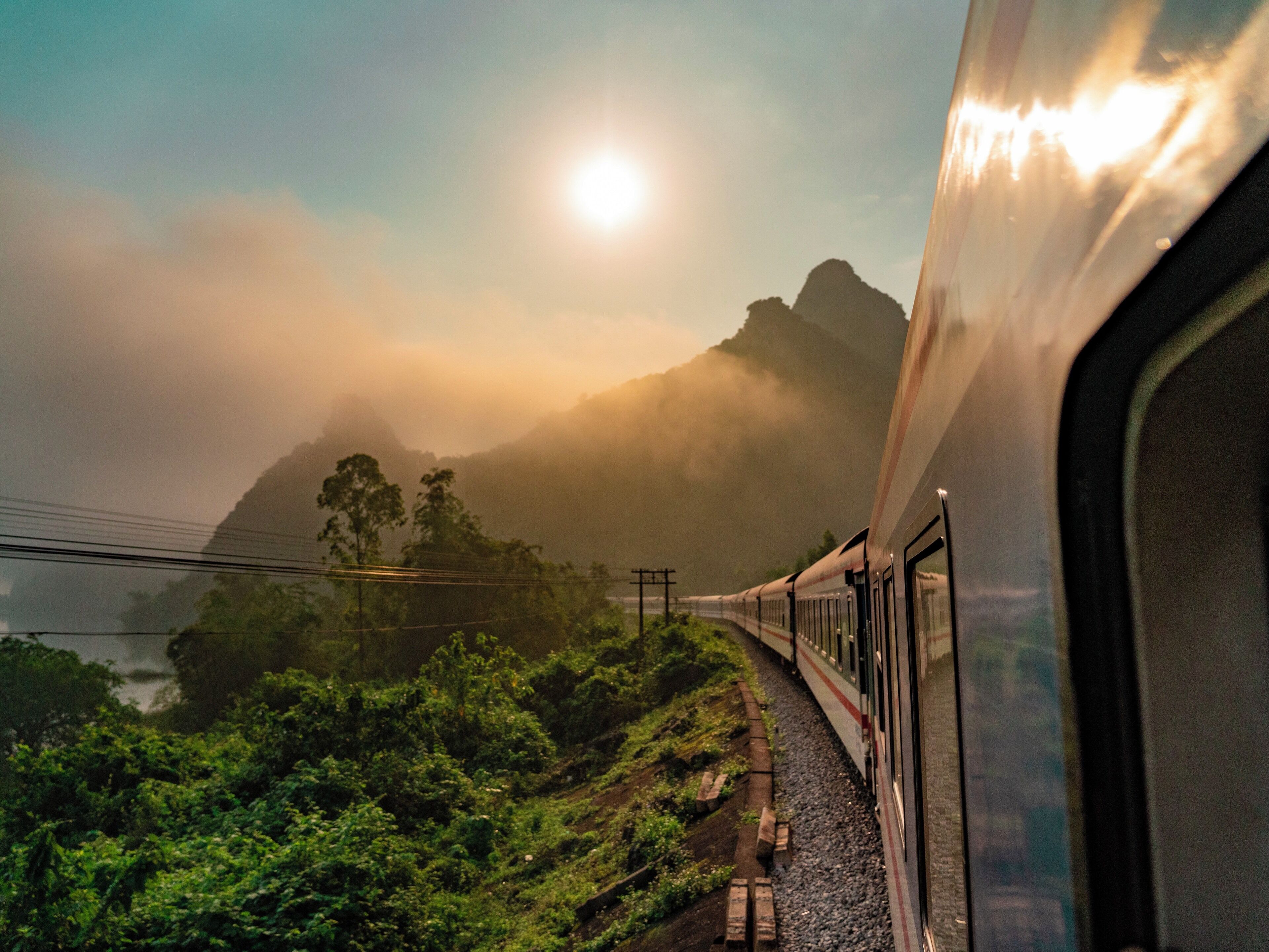 A train traveling through a mountainous landscape with lush greenery and a misty atmosphere.