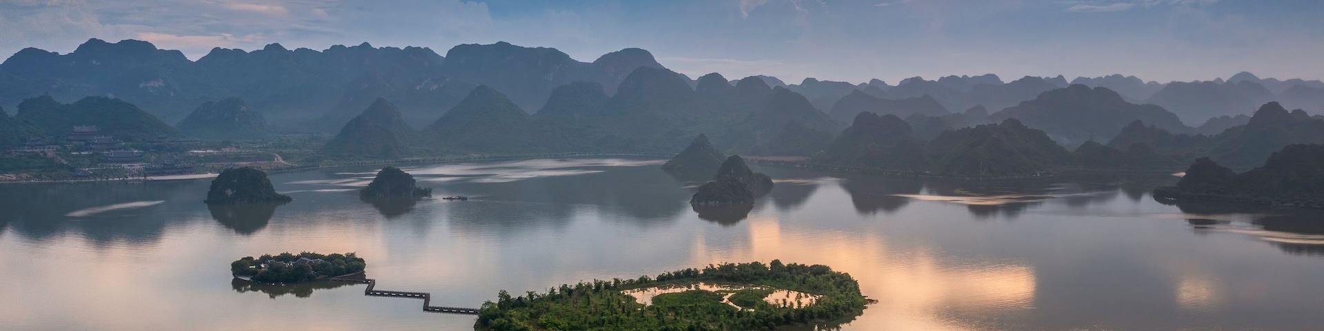 Um lago tranquilo com várias ilhotas cercadas por montanhas.