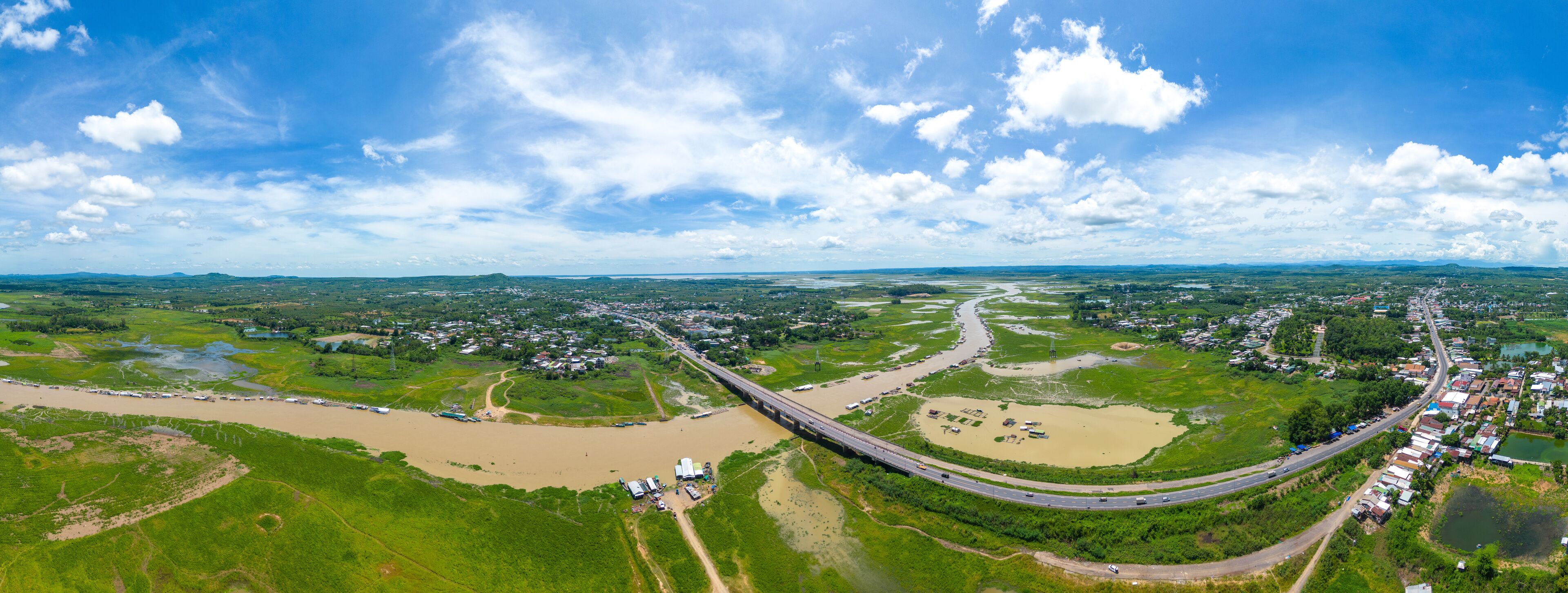 Aerial view of National Route 20 in Dong Nai province, group of floating house on La Nga river, Vietnam with hilly landscape and sparse population around the roads.