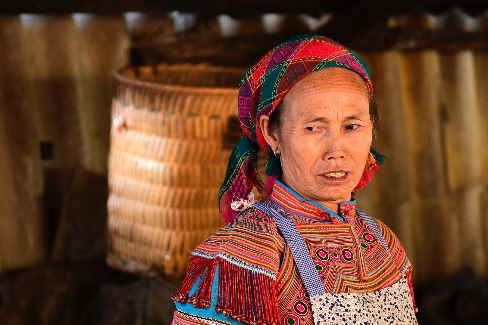 A person in traditional colorful attire with a woven basket in the background.