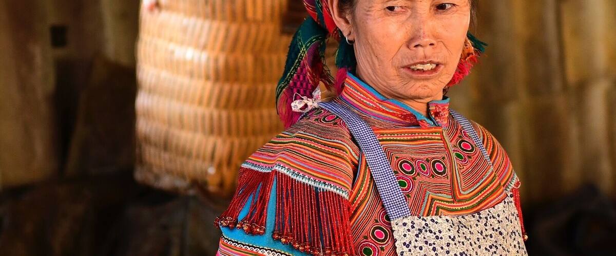 A person in traditional colorful attire with a woven basket in the background.