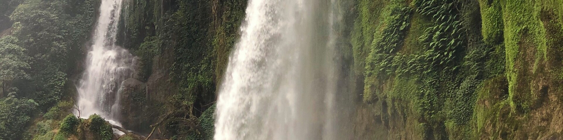 Uma cascata em vários níveis, cercada por vegetação exuberante.