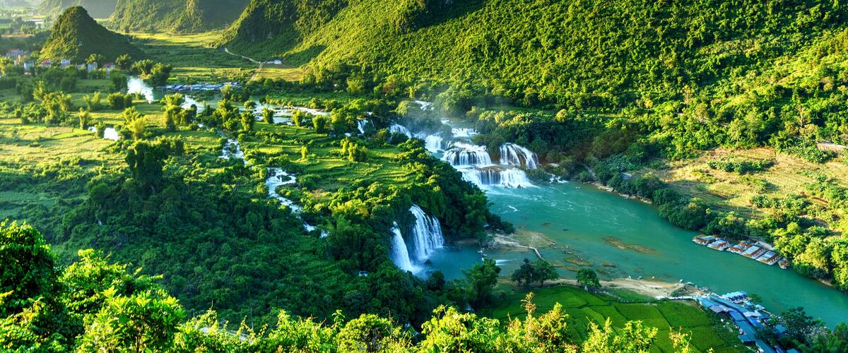 A river flowing through a lush valley with mountains in the background.