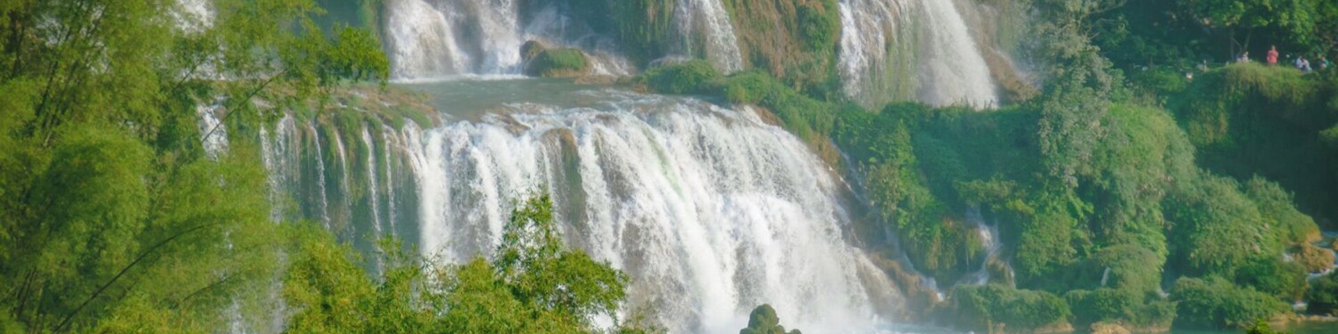 We woke up before sunrise that day, so we would have enough time to make it down to Thac Ban Gioc--right in the border with China--and back to Cao Bang on a single day.
Basically cramming a 2-days ride into a single one, after having committed to a detour that would take us deeper North that we had first expected.
But true to what people had told us, the whole Cao Bang district ended up being a true delight to drive through.
With a uniquely beautiful landscape, I can be sure we all were teary-eyed at different times during our days there, and having reached Ban Gioc within the schedule we had said gave us the necessary morale boost to finish our tour with great energies.
--
Pictured: A group of Chinese tourists approach Thac Ban Gioc in one of the many boats one can hire from the Chinese side of the waterfall--seen from the Vietnamese side.