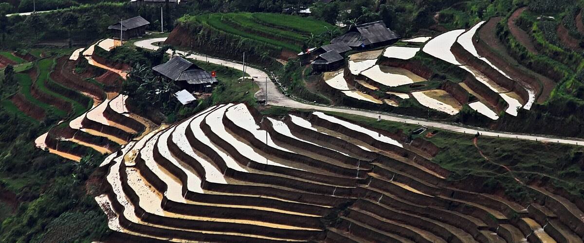 Terraced rice fields, traditional houses, and winding roads in a rural landscape.