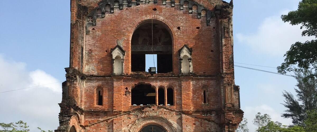 An ancient brick church with a central archway and a bell tower.