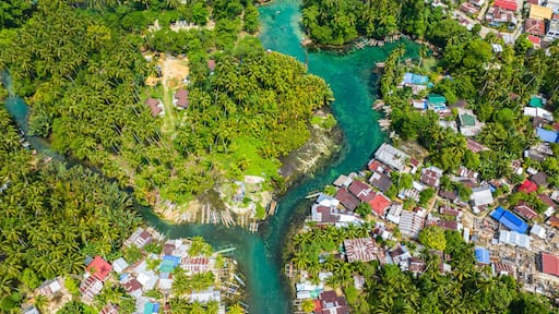 Blue clear water over the Bogac Cold Spring surrounded by villages and tropical forest. Surigao del Sur, Philippines.