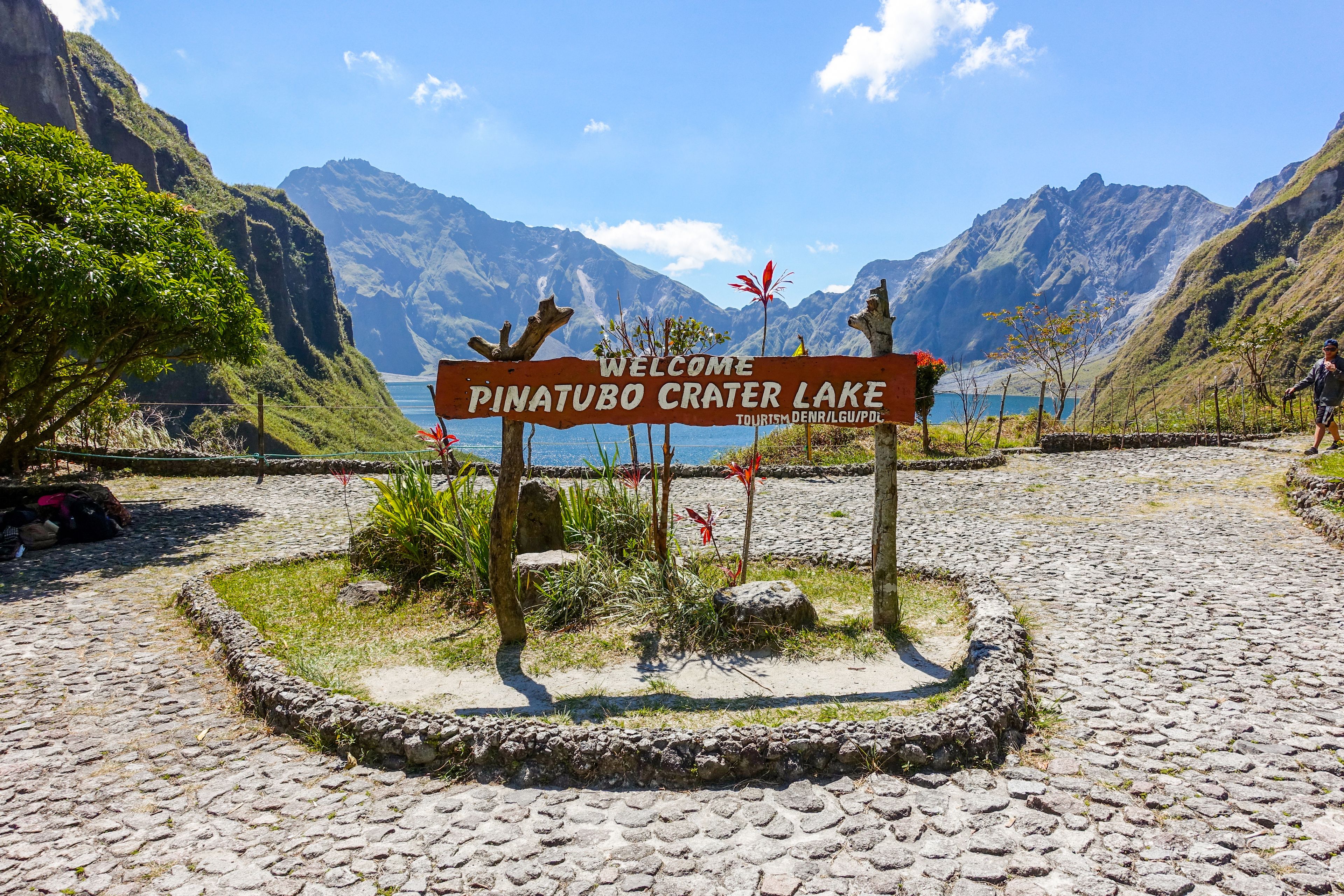 Segnale di benvenuto per il Lago del Cratere Piatubo, circondato da un paesaggio montuoso.