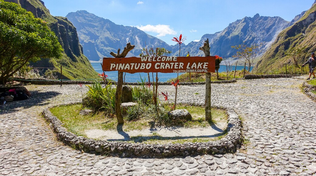 Segnale di benvenuto per il Lago del Cratere Piatubo, circondato da un paesaggio montuoso.