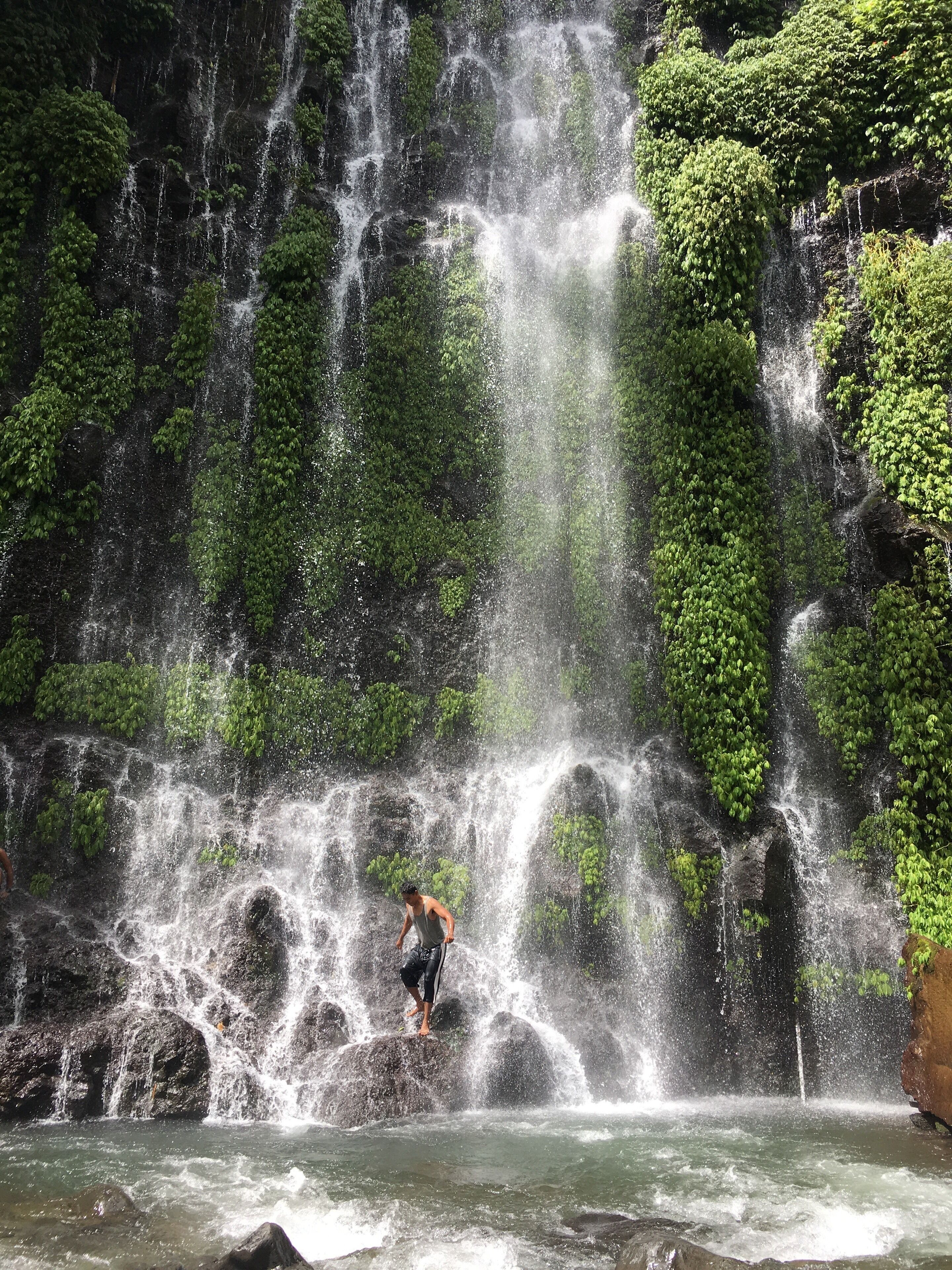 A waterfall with a person jumping in the water.