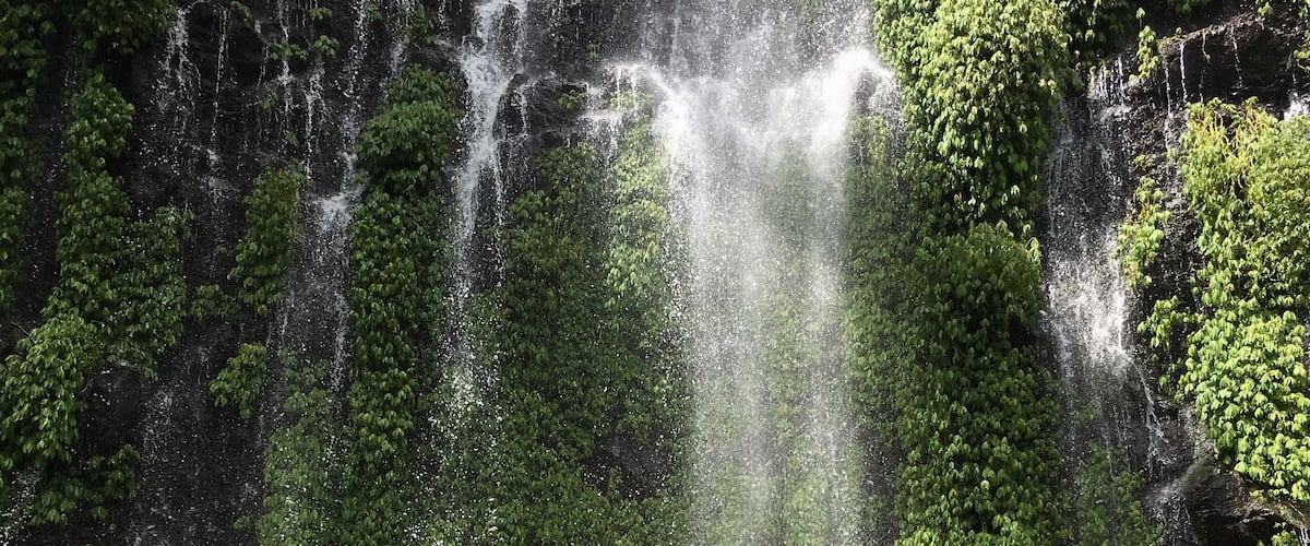 A waterfall with a person jumping in the water.