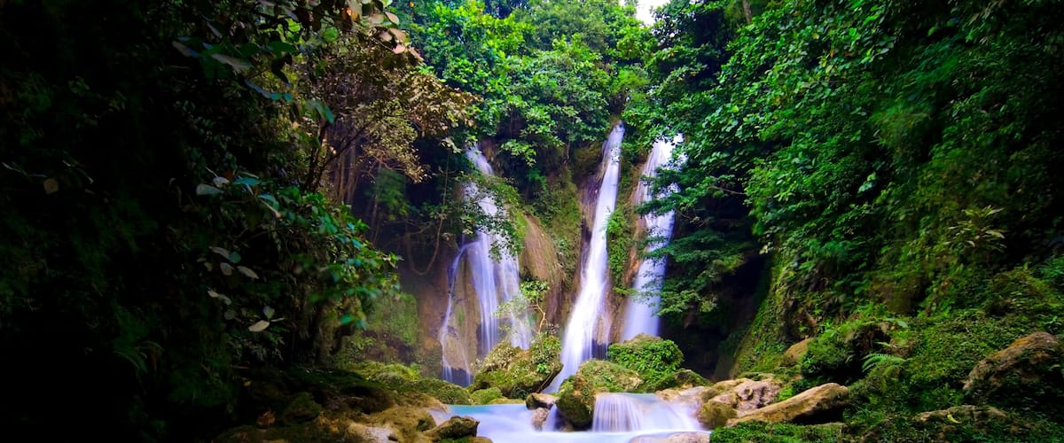 A waterfall cascading into a clear blue pool surrounded by lush greenery.
