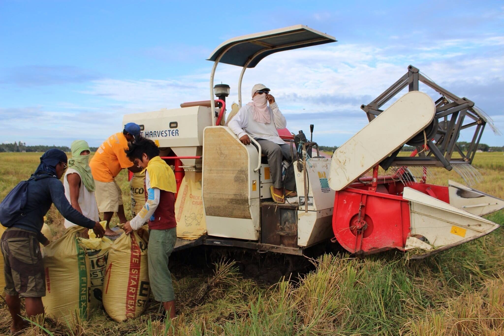 A harvester machine with people around it.
