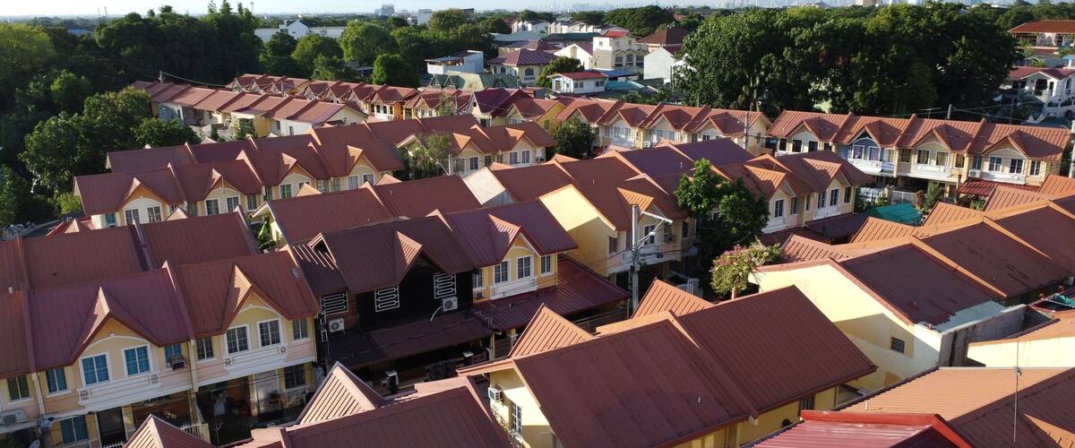 A residential area with closely packed houses featuring red and yellow roofs.