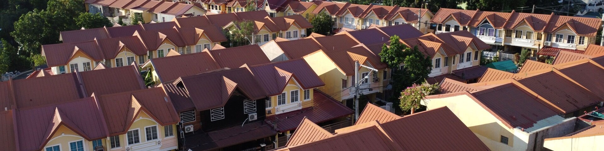 A residential area with closely packed houses featuring red and yellow roofs.