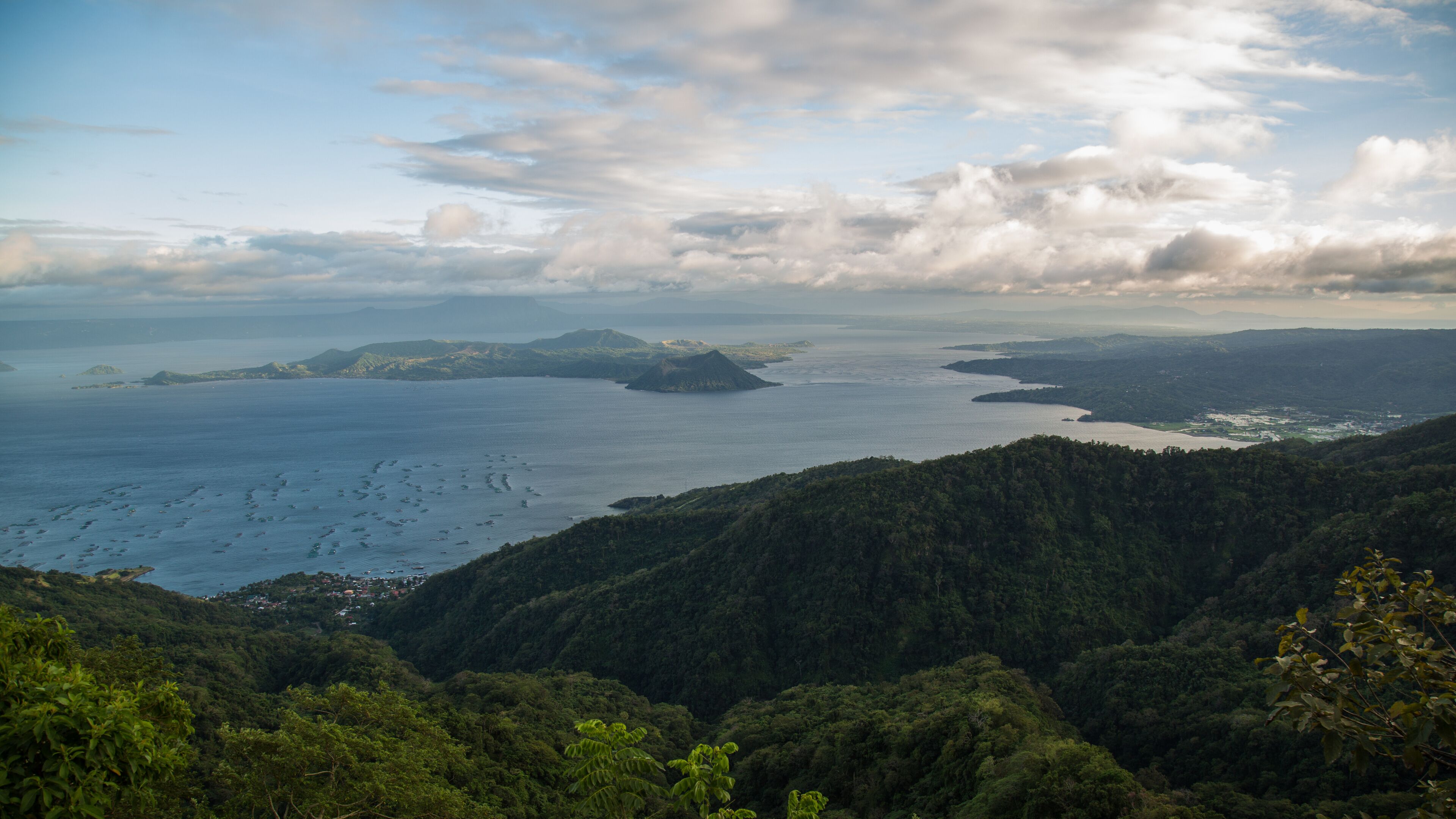 A coastal landscape with dense forests, a large body of water, and several small islands.