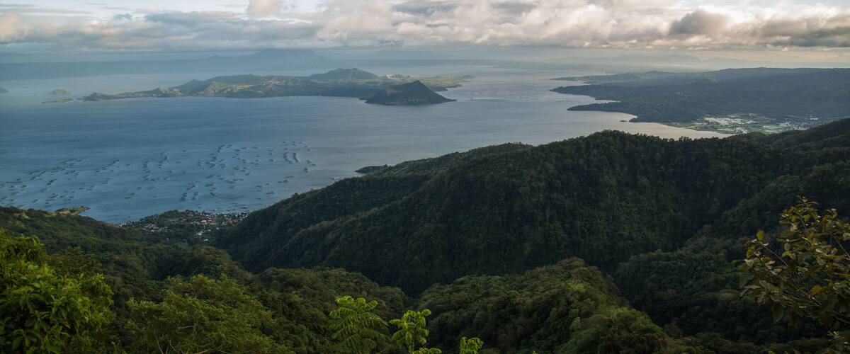 A coastal landscape with dense forests, a large body of water, and several small islands.