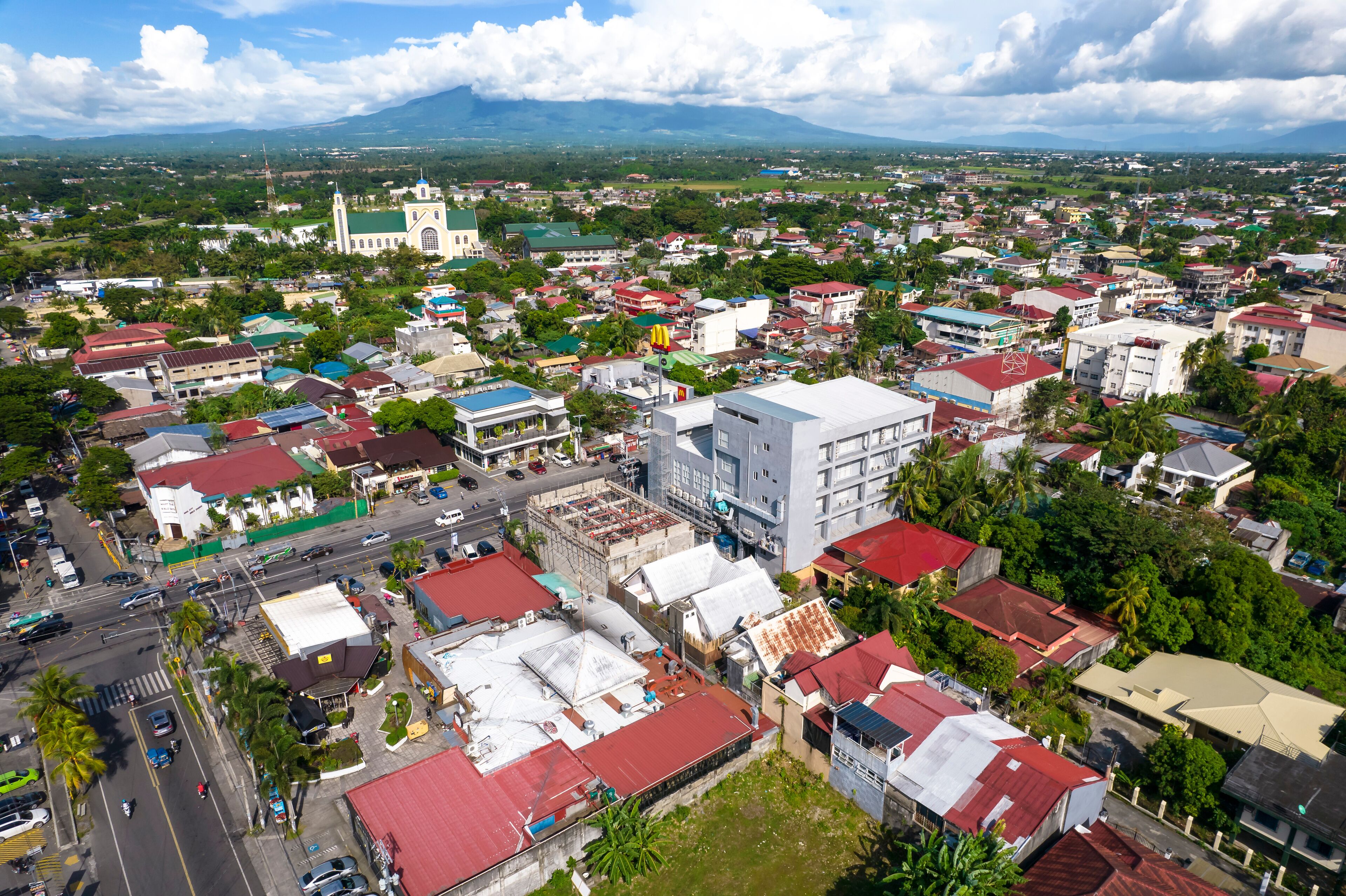 A cityscape with a prominent church, a mix of residential and commercial buildings, and a mountainous backdrop.