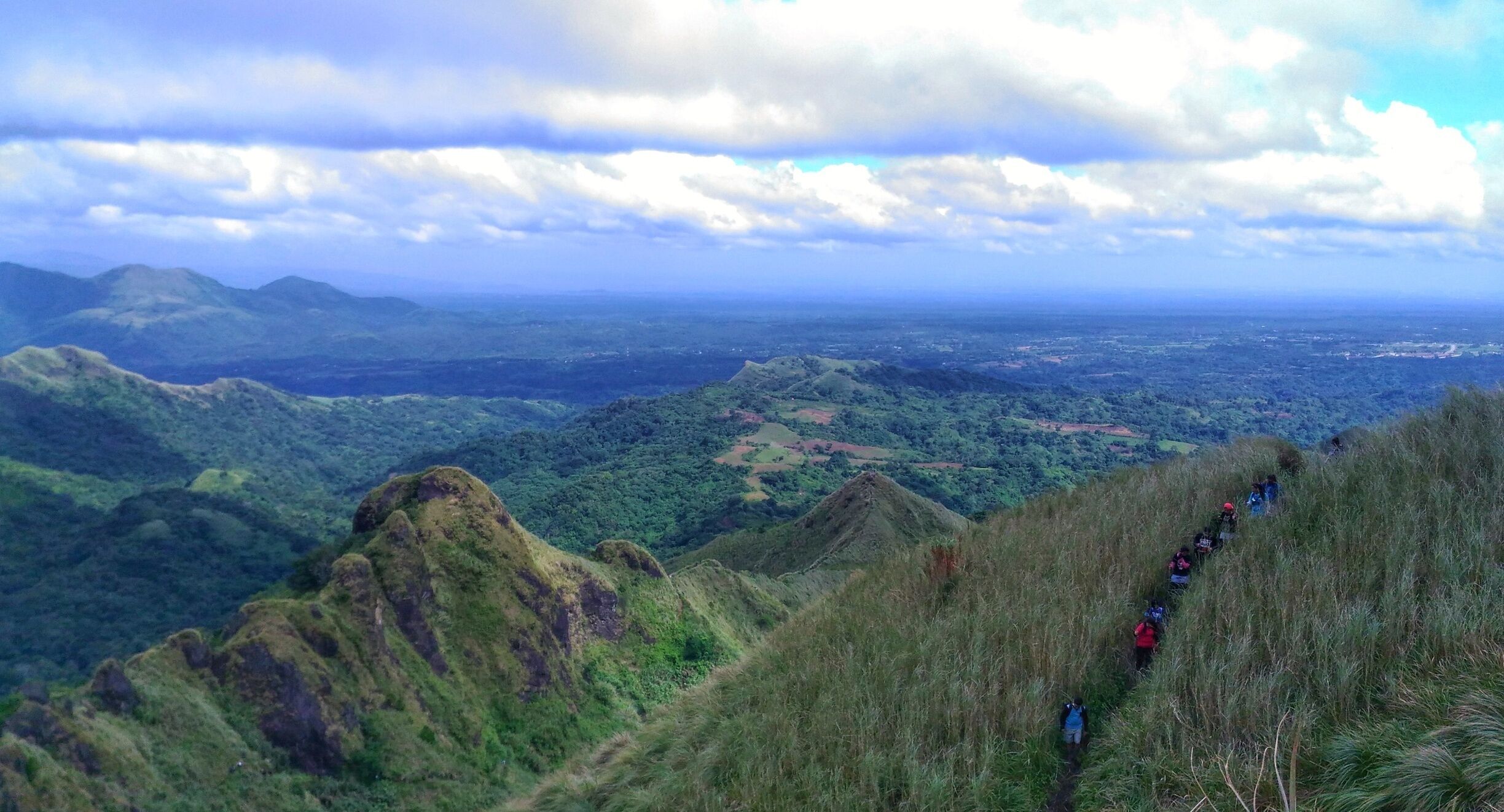 A mountainous landscape with a hiking trail and lush greenery.