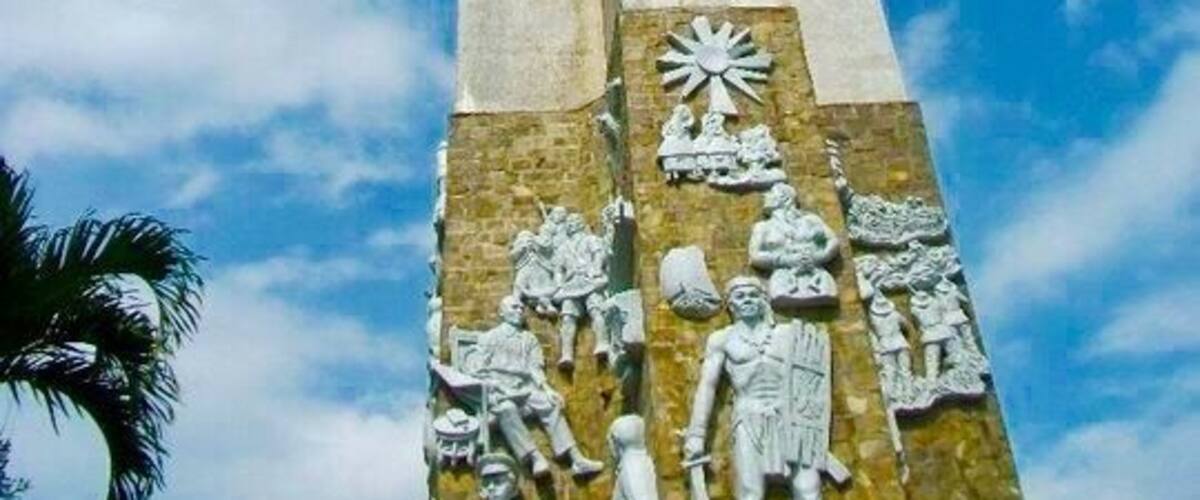 Een hoog monument met een kruis bovenop en reliëfbeeldhouwwerken aan de voet.