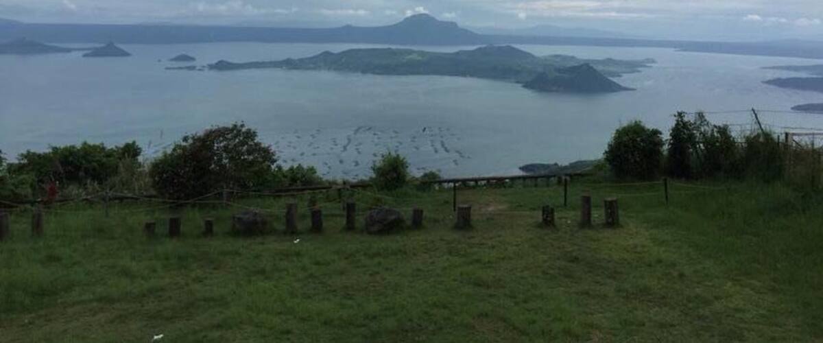 A coastal landscape with a grassy foreground, a fence, and a view of the sea with distant islands.