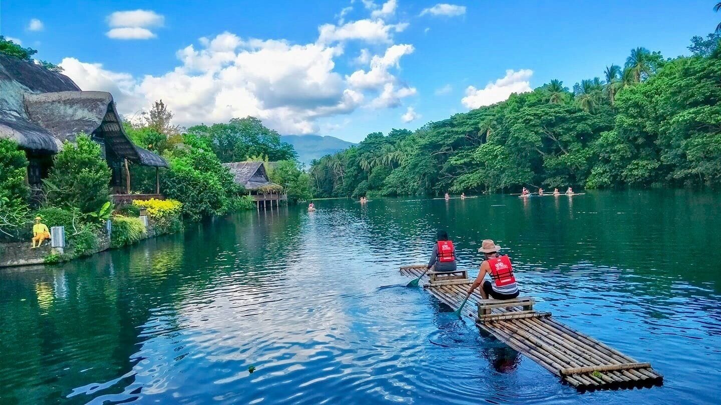 A river with two canoes, one with a person paddling and another with two people.