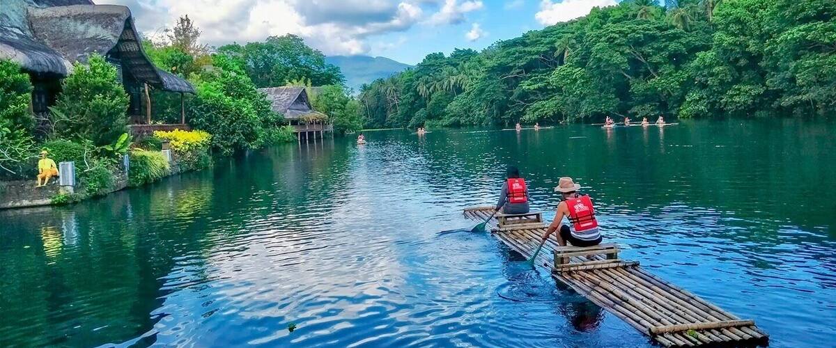 A river with two canoes, one with a person paddling and another with two people.