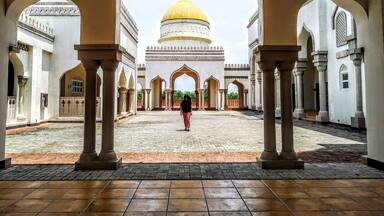 A courtyard with a large golden dome and arches.