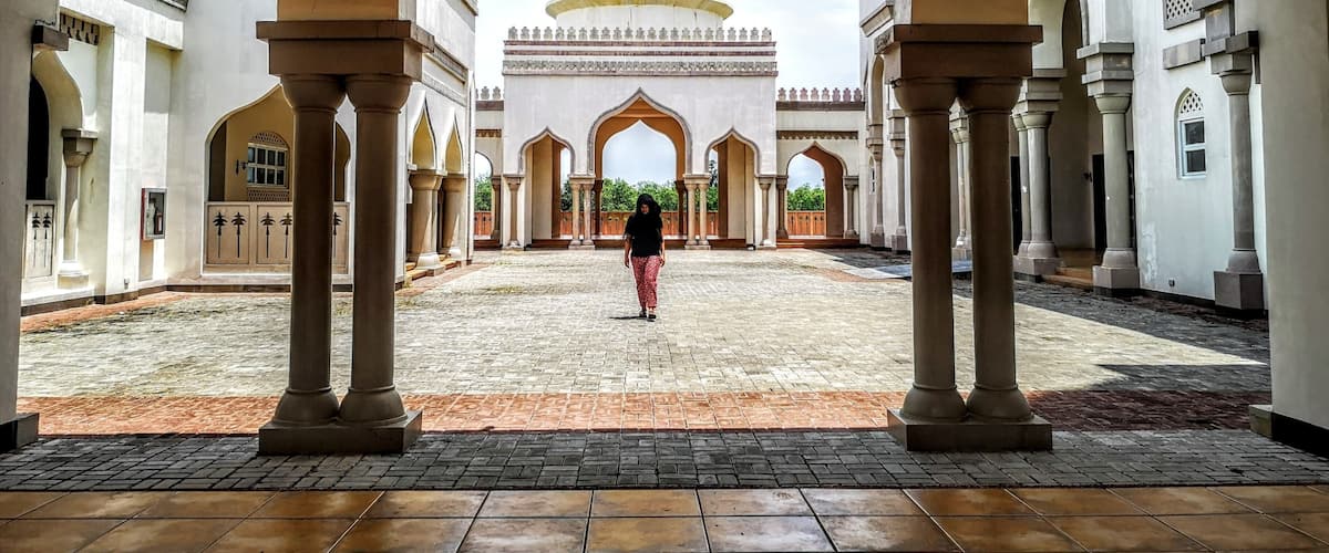 A courtyard with a large golden dome and arches.
