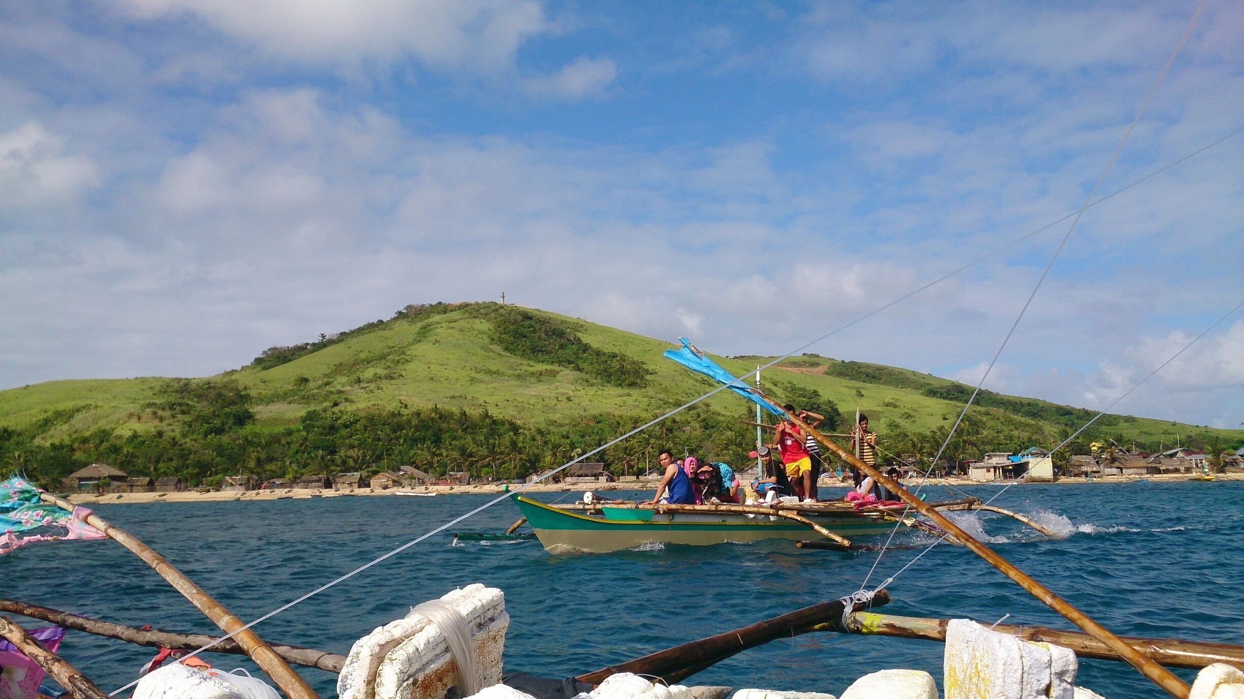 A boat on calm waters with a green hill in the background.