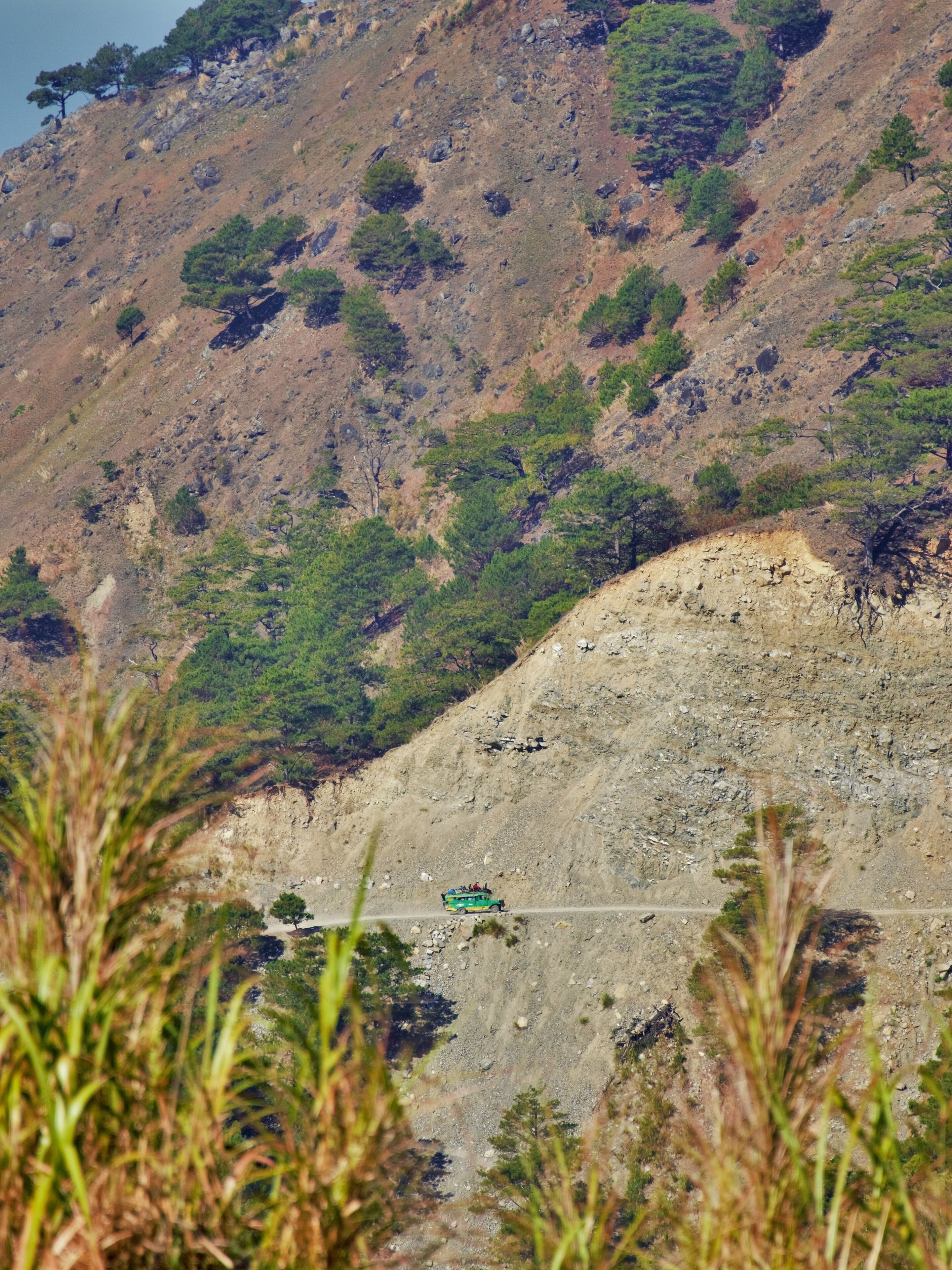A rugged mountain landscape with sparse vegetation and a winding road.