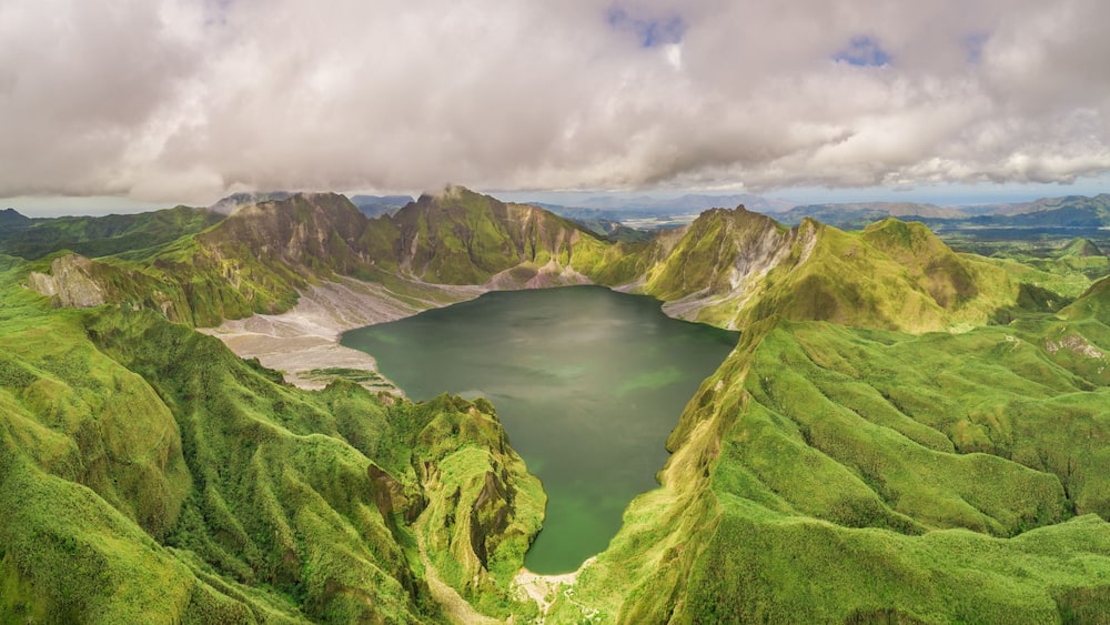 A green valley with a lake surrounded by mountains.