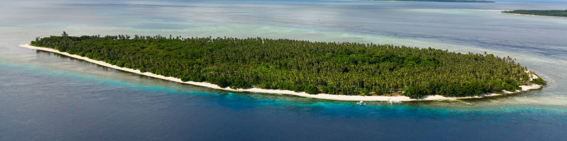 Tropical island in the blue sea with a coral reef and the beach. Balabac, Palawan. Philippines.