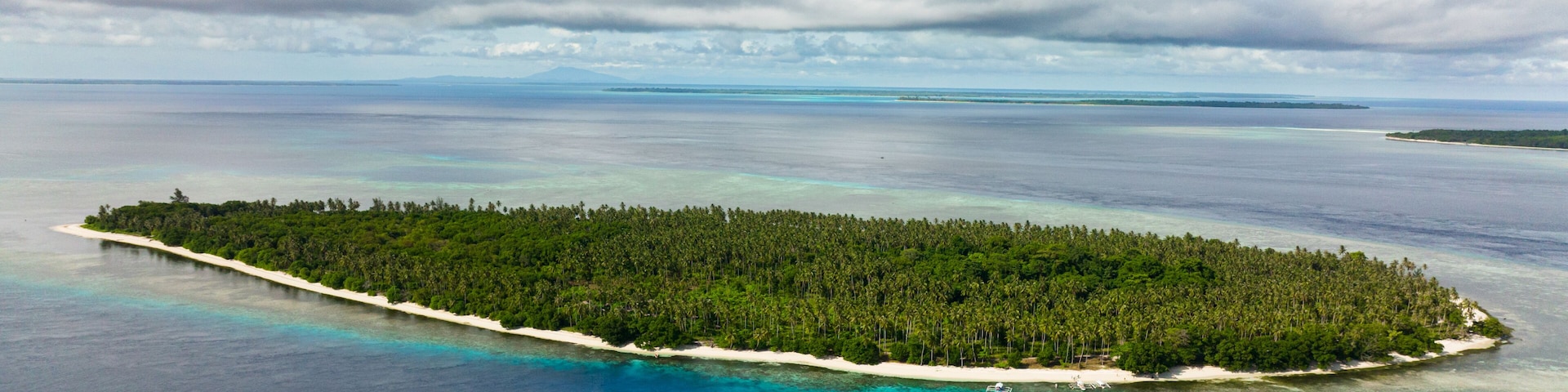 Tropical island in the blue sea with a coral reef and the beach. Balabac, Palawan. Philippines.