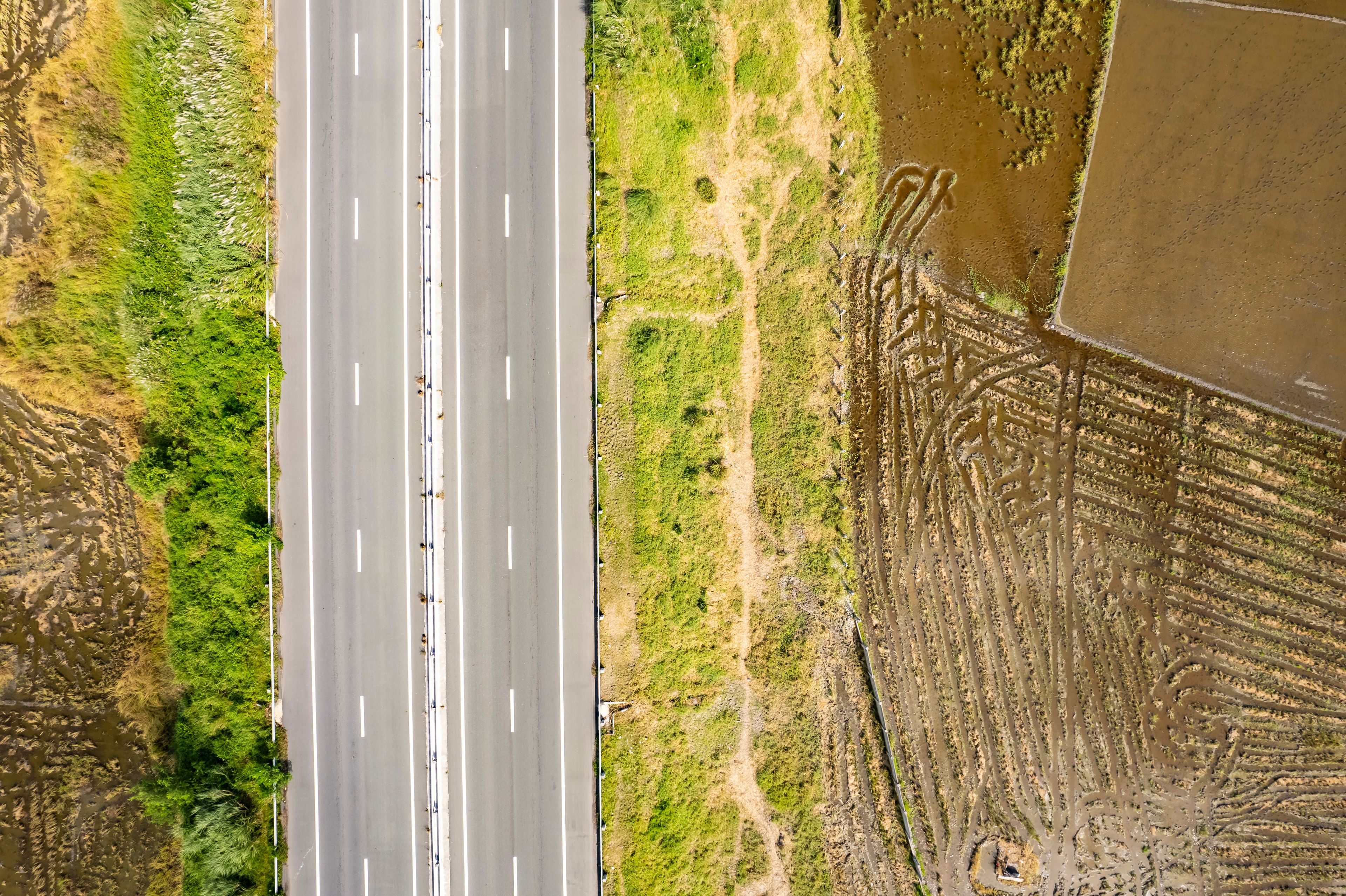 A highway with multiple lanes, surrounded by green vegetation and a large body of water.