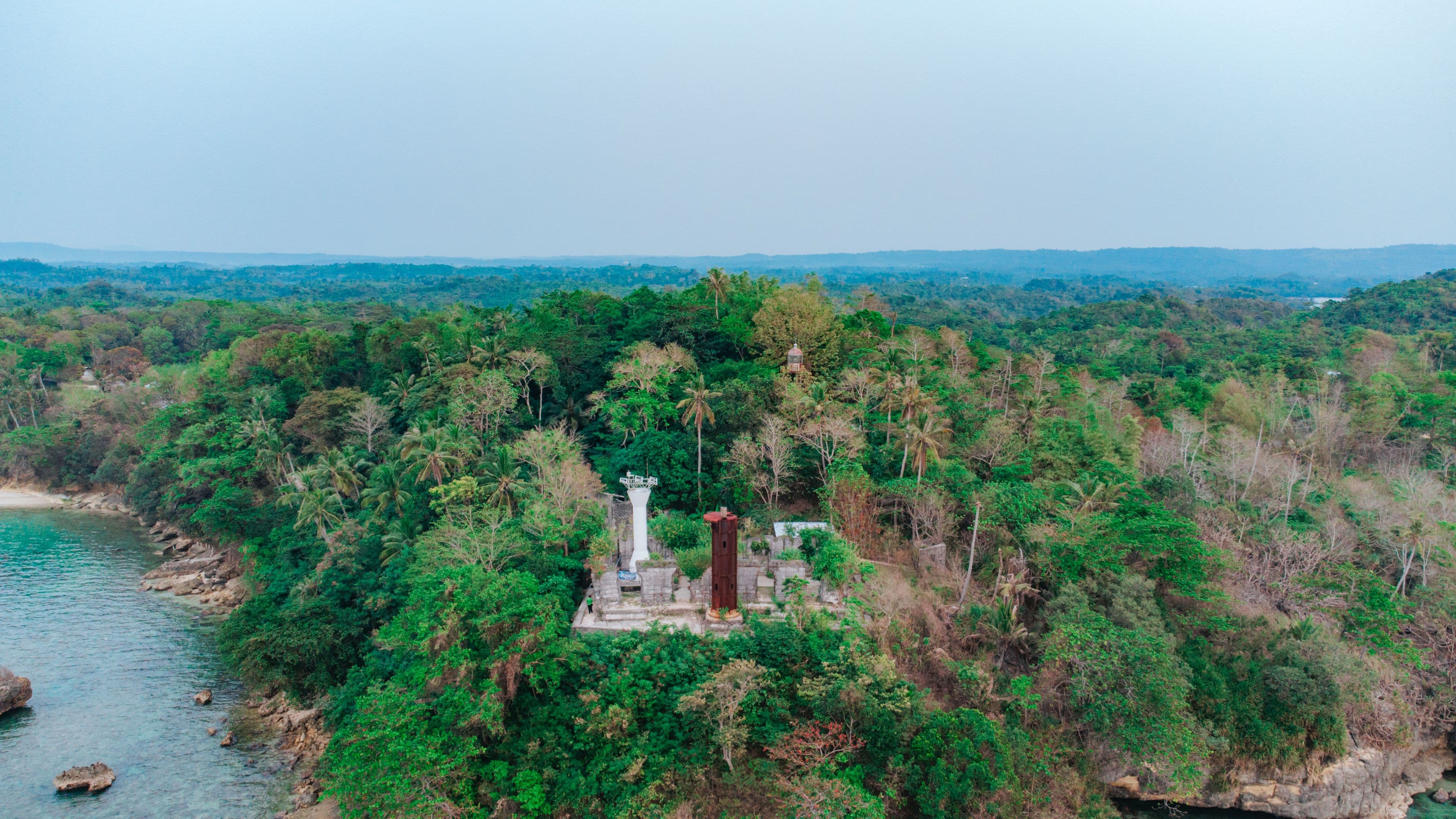 A coastal landscape with a temple-like structure surrounded by dense tropical vegetation.