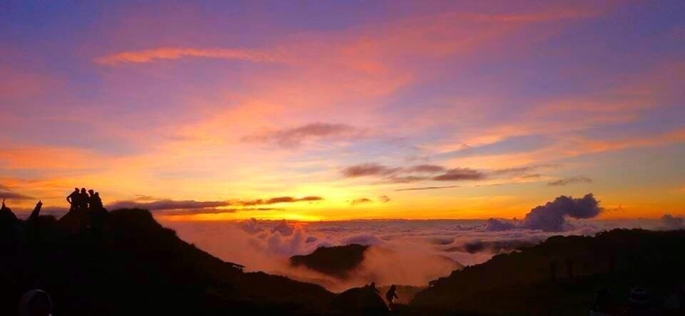 A sunset over a mountainous landscape with clouds below.