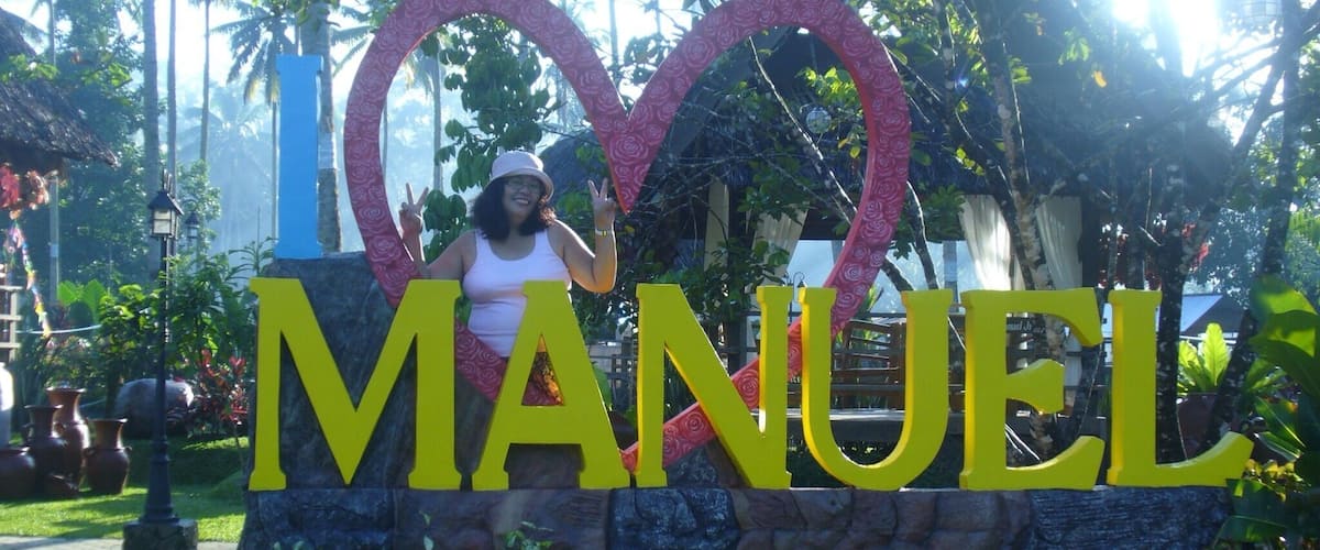 A sign with the word 'MANUEL' and a heart shape made of pink flowers.