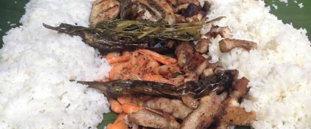 A long table with white rice and various seafood dishes.