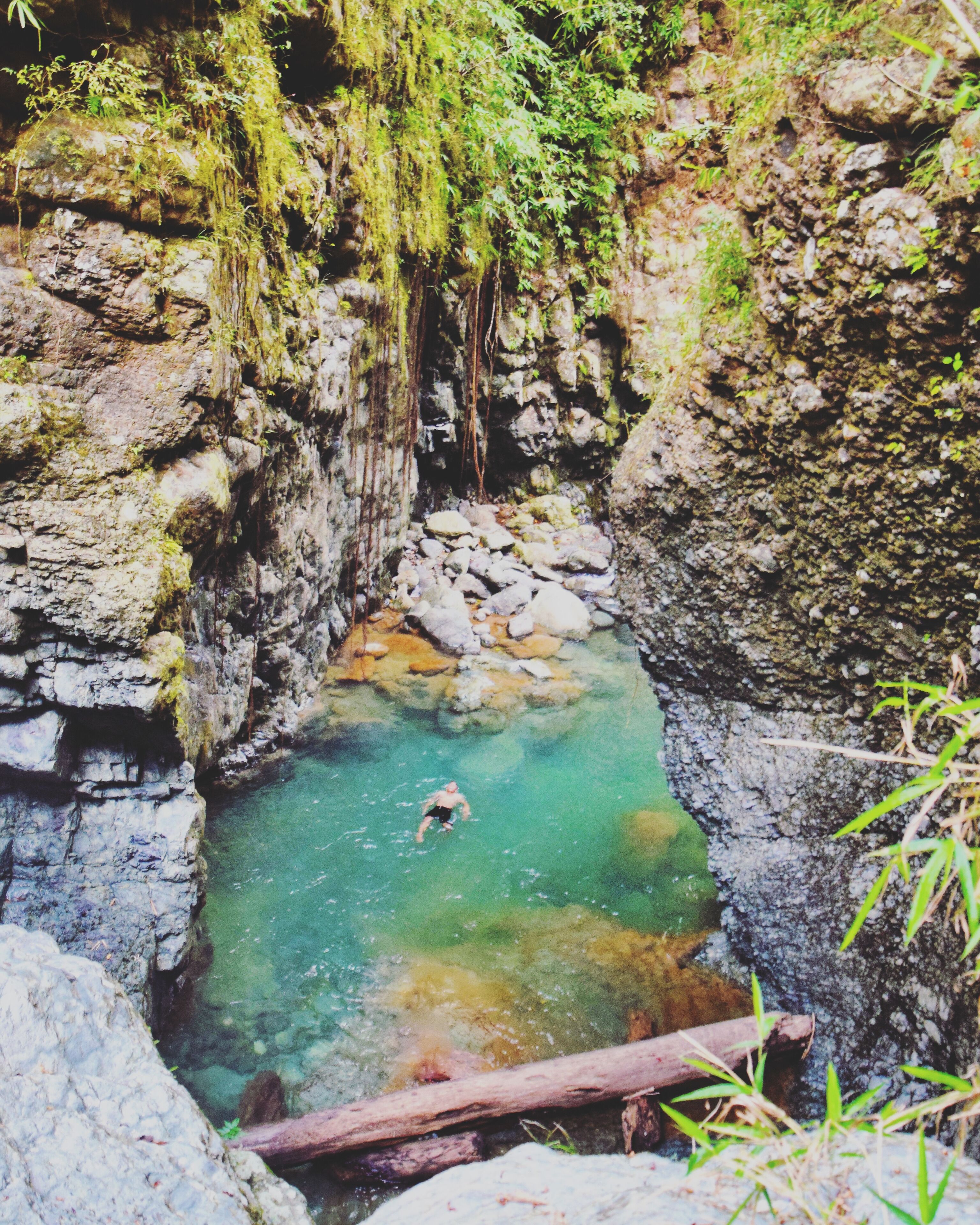 A rocky gorge with clear turquoise water and a person swimming.