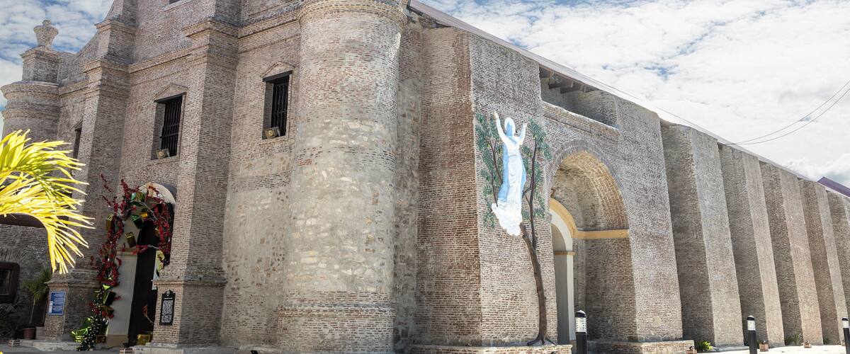 A historic church with a large mural, brick walls, and a clear sky.