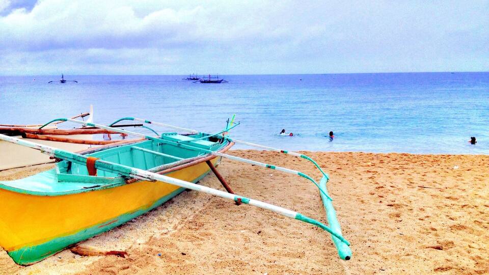A beach with a yellow boat and a calm sea.