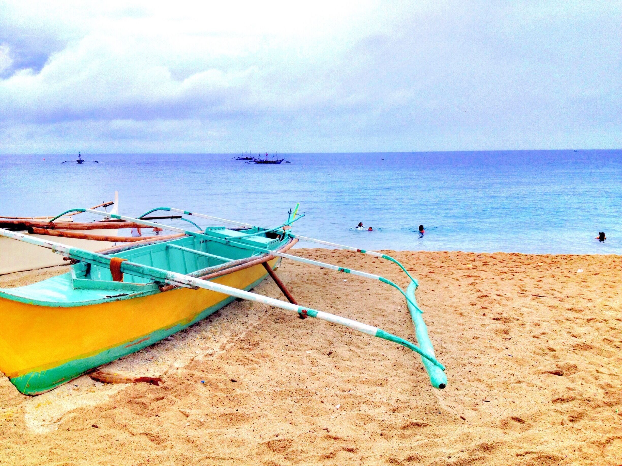 A beach with a yellow boat and a calm sea.