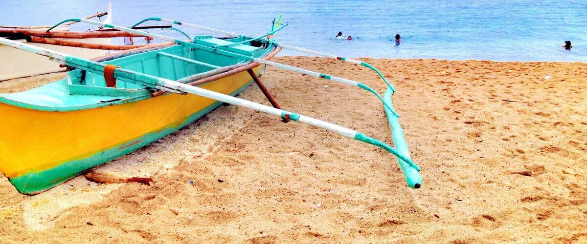 A beach with a yellow boat and a calm sea.