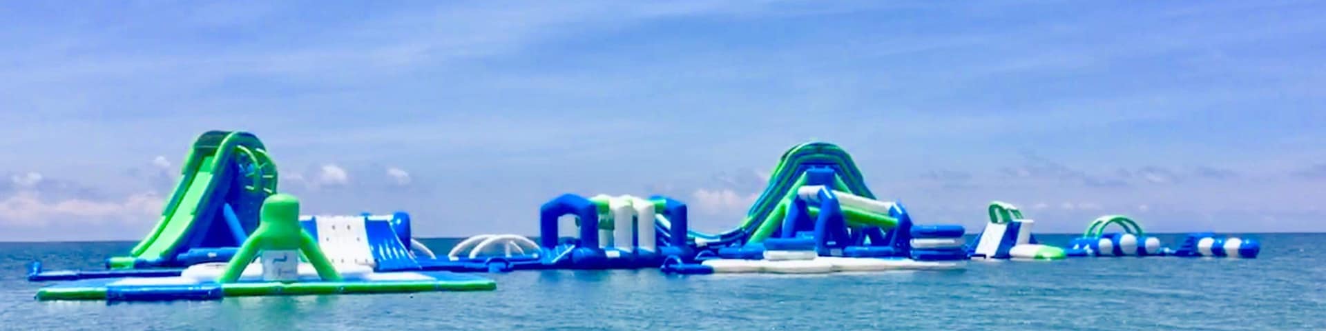 Um parque aquático inflável com escorregas e estruturas de recreação numa praia.