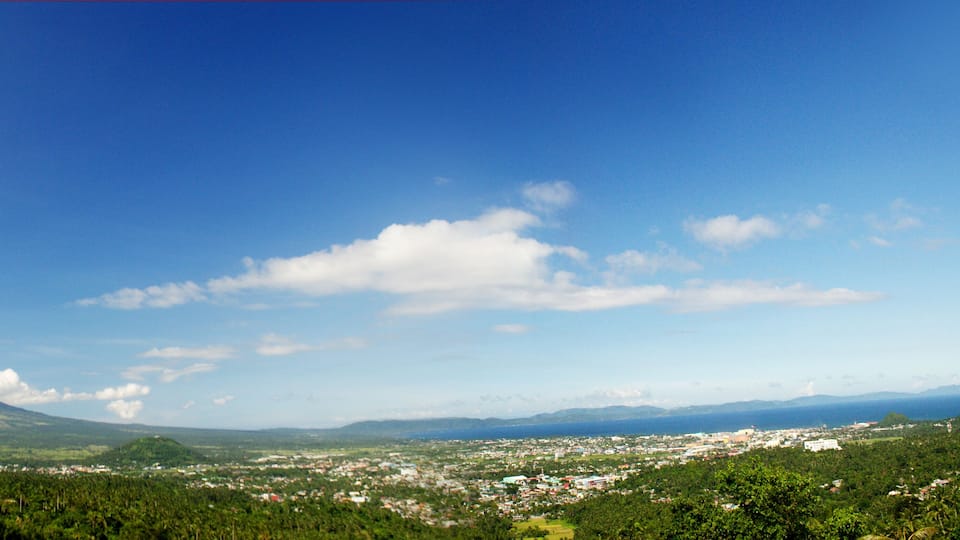 A volcano with a town in the foreground and mountains in the distance.