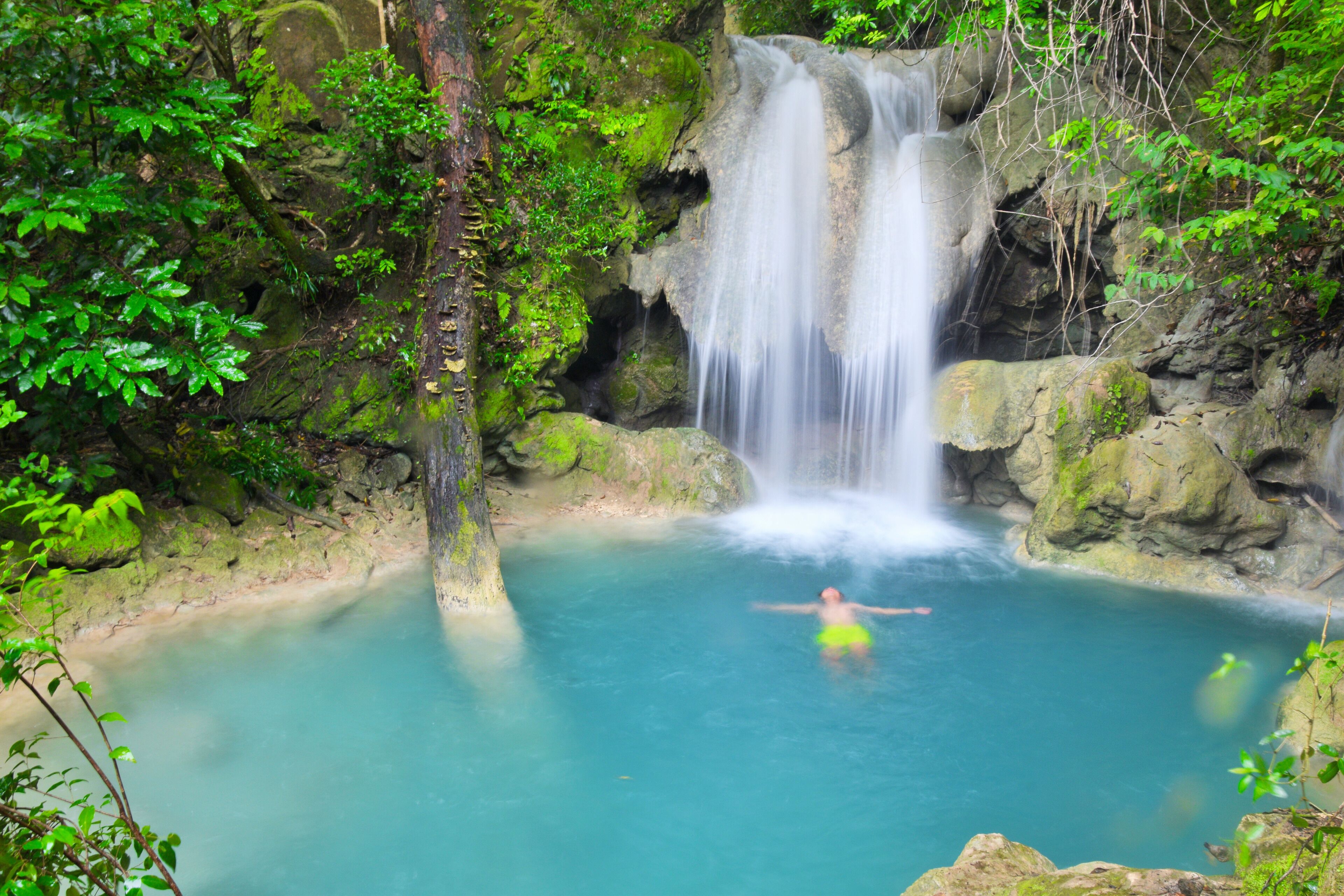 A waterfall in a forested area with clear blue water.
